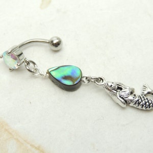 May include: Silver body piercing with a clear iridescent gem, a dangling abalone shell charm, and a mermaid charm.