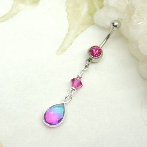 May include: A silver body jewelry piece with a pink gem and a teardrop-shaped iridescent gem hanging from a chain.