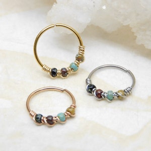May include: Three hoop earrings with colourful beads. The hoops are made of gold, silver, and rose gold. The beads are a mix of turquoise, brown, and black.