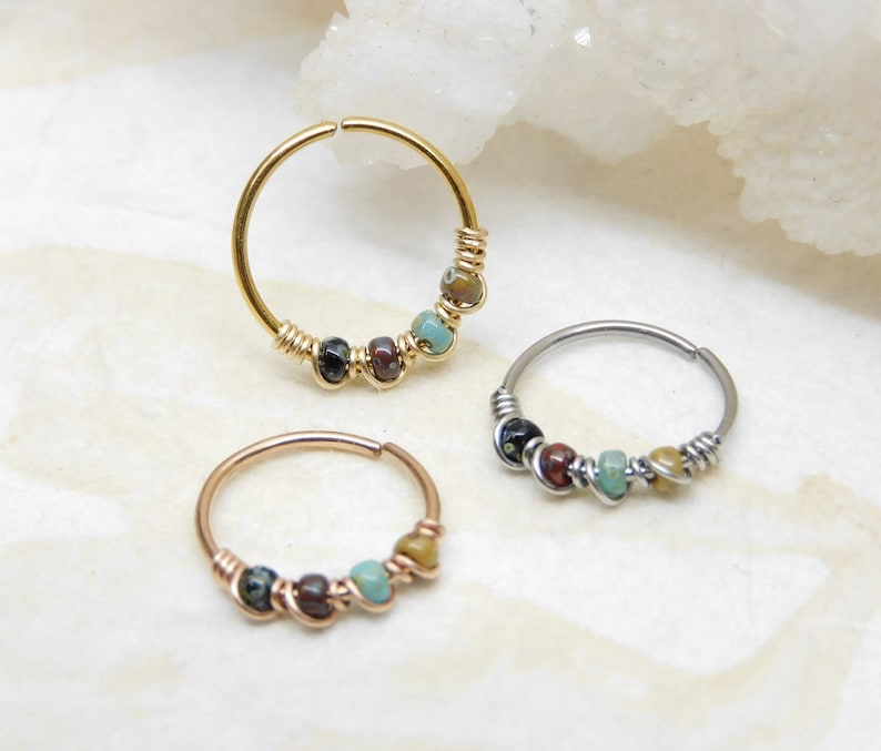 May include: Three hoop earrings with colourful beads. The hoops are made of gold, silver, and rose gold. The beads are a mix of turquoise, brown, and black.