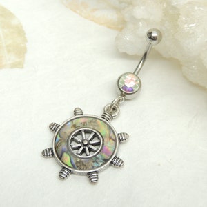 May include: Silver belly button ring with a clear iridescent gem and a silver ship's wheel charm with a mother-of-pearl inlay.