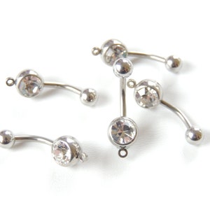 May include: Five silver belly button rings with clear crystal stones. The rings are curved and have a ball on one end and a crystal on the other.