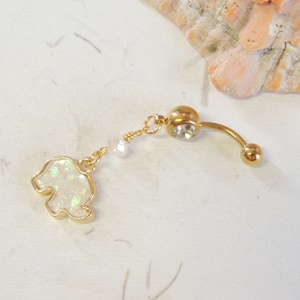 May include: Gold belly button ring with a clear crystal and a dangling charm of a white iridescent elephant.