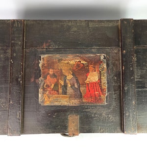 May include: A dark wooden box with a hinged lid. The lid features a painted scene of a religious gathering, with figures in red, blue, and yellow clothing. The box has a metal latch and hinges.