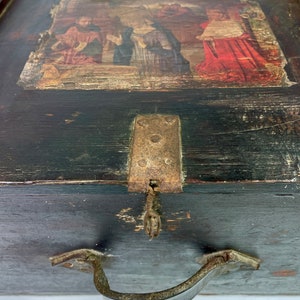 May include: A vintage wooden box with a hinged lid, a metal latch, and a metal handle. The lid features a faded painted scene of people in a landscape.