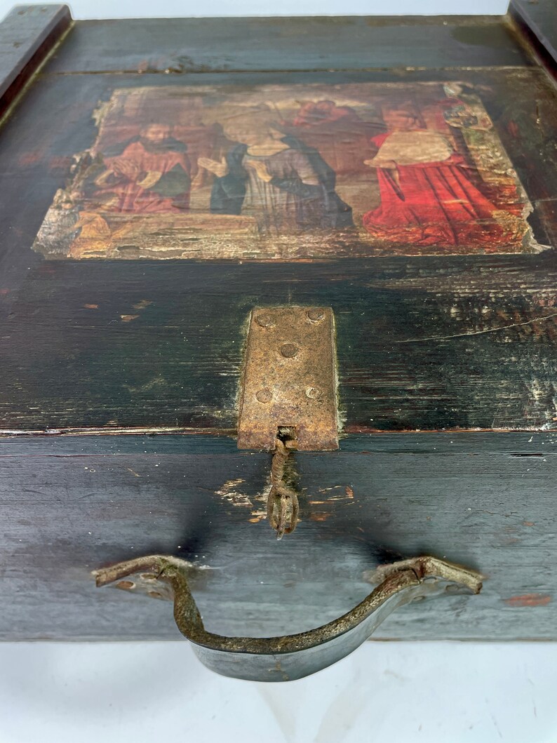 May include: A vintage wooden box with a hinged lid, a metal latch, and a metal handle. The lid features a faded painted scene of people in a landscape.