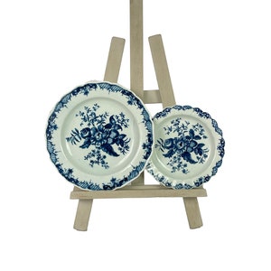May include: Two blue and white porcelain plates with floral designs, displayed on a wooden easel.