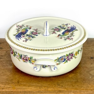 May include: White ceramic casserole dish with a lid. The dish has a floral design with blue and green birds. The lid has a blue handle.