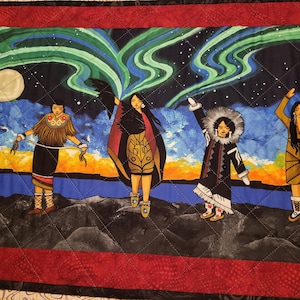 May include: Five women in traditional clothing stand in front of a dark blue background with green and blue aurora borealis above them. The women are wearing colorful clothing with geometric patterns and are holding various objects. The background is filled with stars.