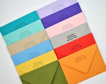 May include: A collection of ten envelopes in various colors, each with the same address printed in black ink: Tamara Moore, 12345 Oak Avenue, Wood City, FL 33333.
