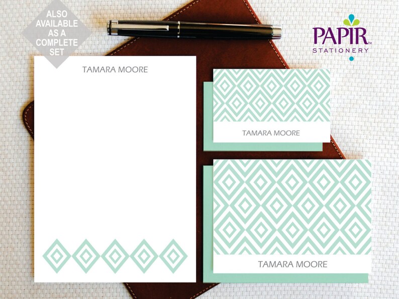 Op de afbeelding: Een set briefpapier met een geometrisch patroon in tinten groen en wit. Het briefpapier bevat een notitieblok met de naam "TAMARA MOORE" bovenaan en een set kaartjes met hetzelfde patroon en dezelfde naam.