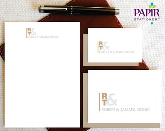 Puede incluir: Un juego de tres tarjetas de papelería con un logotipo marrón y gris que dice "R&T" y "Robert & Tamara Moore". Las tarjetas están sobre una superficie de cuero marrón.