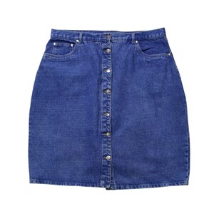 May include: A denim skirt in a medium blue wash. The skirt features a button-down front closure, two front pockets, and a classic A-line silhouette. The skirt is made of a durable denim fabric.