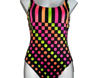 May include: A black swimsuit with a geometric pattern in pink, green, and orange. The pattern features stripes, squares, and polka dots.