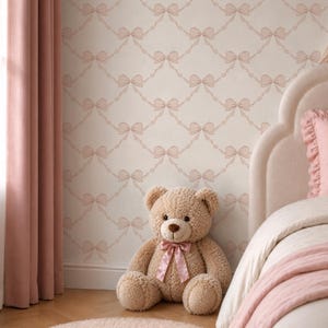 May include: A cozy bedroom scene featuring a plush teddy bear with a pink bow, a bed with pink bedding, and a patterned wallpaper with pink bows. A pink rug and curtains complete the soft, inviting aesthetic.