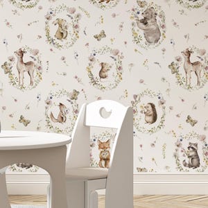 May include: A whimsical wallpaper design featuring woodland animals such as foxes, raccoons, and deer, each framed by floral wreaths. The background is a soft off-white, with scattered butterflies and flowers. A white child's table and chair are in the foreground.