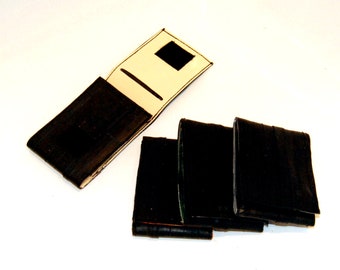 May include: Four black leather wallets, one with a cream colored interior and a black flap. The wallets are made from recycled materials.