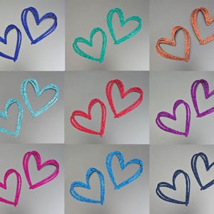 May include: Nine pairs of glittery heart shapes in various colours, including blue, green, orange, turquoise, red, purple, pink, and navy. Each heart pair is outlined with a contrasting colour.