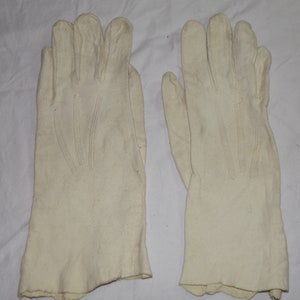 May include: A pair of white cotton gloves. The gloves are made of a soft, smooth fabric and have a simple design.