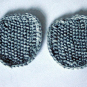 Puede incluir: Dos círculos redondos de tejido de punto en un patrón azul y blanco. Los círculos tienen un diámetro de aproximadamente 5 cm.