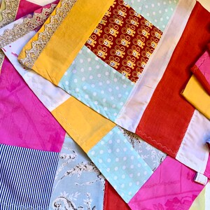 Może przedstawiać: Zestaw kolorowych patchworkowych podkładek pod talerze z różnymi wzorami, w tym kropkami, paskami i kwiatowymi motywami. Podkładki są wykonane z różnych tkanin i mają rustykalny, ręcznie robiony wygląd.