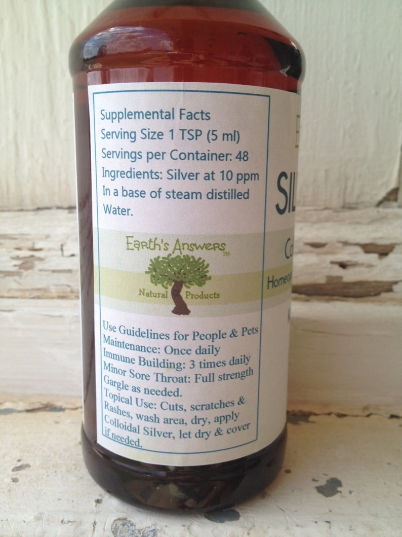 May include: A brown glass bottle with a white label that reads "Earth's Answers Natural Products". The label also includes the text "Supplemental Facts", "Serving Size 1 TSP (5 ml)", "Servings per Container: 48", "Ingredients: Silver at 10 ppm", "In a base of steam distilled Water.", and "Use Guidelines for People & Pets".