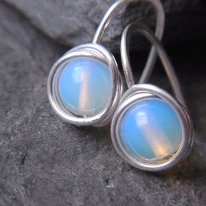 Peut inclure: Une paire de boucles d'oreilles en fil d'argent avec des pierres d'opale bleu clair.