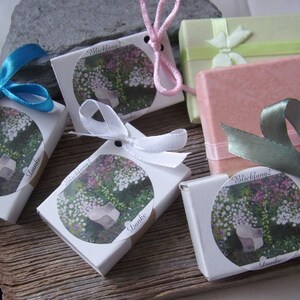 May include: Five small white boxes with a floral design and the text "Blickfang!" and "Danke". Each box is tied with a different colored ribbon: blue, white, pink, green, and pink.