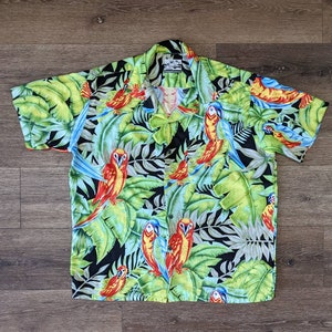 May include: A black short-sleeved button-up shirt with a tropical print featuring green leaves and colorful parrots.