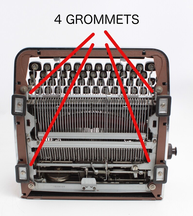 May include: A close-up view of the back of a vintage typewriter with the text "4 GROMMETS" written above the machine. The grommets are visible on the top of the typewriter.