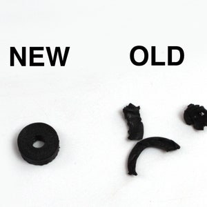 May include: A comparison of a new and old rubber washer. The new washer is a solid black ring. The old washer is broken into three pieces.