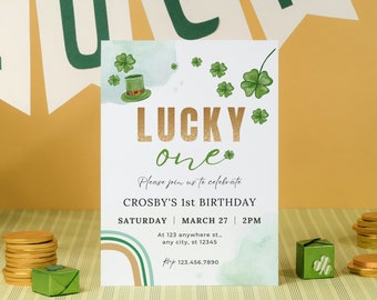 May include: A green and gold invitation card with a shamrock and leprechaun hat design. The text reads "LUCKY one" and "Please join us to celebrate Crosby's 1st Birthday, Saturday, March 27, 2PM, At 123 anywhere st., any city, st 12345, Bop 123.456.7890".