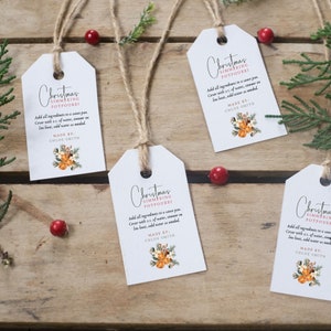 May include: Four white gift tags with a rustic twine string. Each tag features a Christmas-themed design with a floral illustration and the text "Christmas Simmering Potpourri". The text includes instructions for using the potpourri, along with the words "Made By: Chloe Smith".