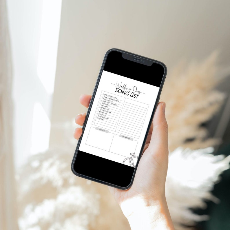 May include: A black smartphone displaying a wedding day song list checklist. The checklist includes sections for "Must Play" and "Do Not Play" songs. The phone is held in a person's hand.