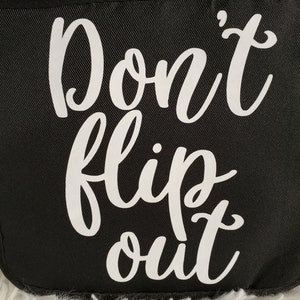 May include: Black fabric tote bag with white text that reads "Don't flip out".