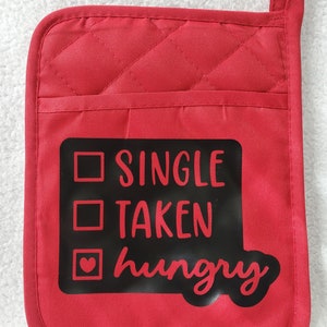 May include: Red quilted oven mitt with a black square patch that says "Single, Taken, Hungry" with a heart in the box next to "Hungry".