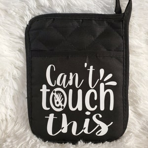 May include: Black quilted oven mitt with white text that reads "Can't touch this" with a stylized handprint symbol.