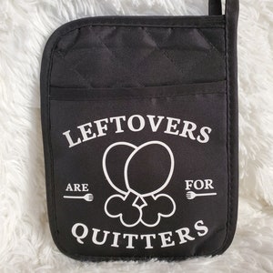 May include: Black quilted oven mitt with the text "Leftovers are for Quitters" in white. The mitt features a pocket and a loop for hanging. The design includes a graphic of two chicken drumsticks.