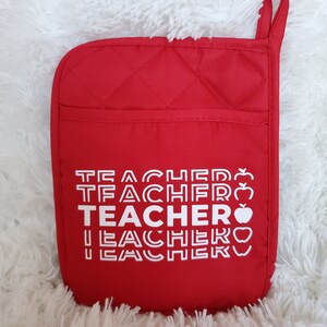 May include: Red quilted oven mitt with a white design that says "TEACHER" four times with an apple graphic next to each word.