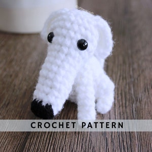 May include: White crocheted dog amigurumi with black eyes and nose. CROCHET PATTERN text is visible at the bottom of the image.