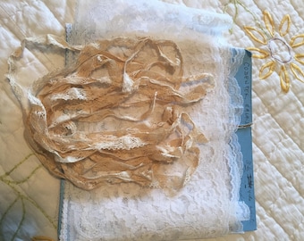 May include: A close-up of a pile of ivory lace trim. The lace is delicate and intricate, with a floral pattern. The lace is on top of a piece of white lace fabric. The fabric is labeled "Codeutex Etalay 3/8" wide lace"
