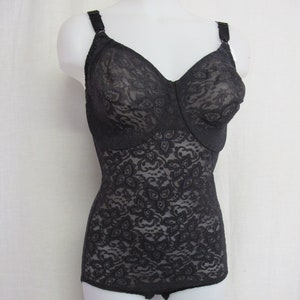 May include: Black lace body suit with adjustable straps. The suit has a floral pattern and is made of a sheer fabric.