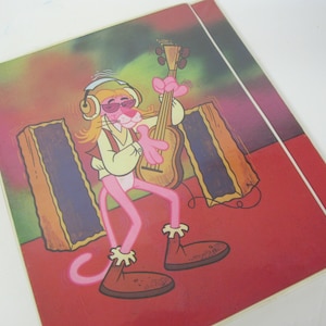 May include: A pink cartoon panther wearing headphones and playing a guitar with two large speakers behind it. The background is a colourful abstract design.