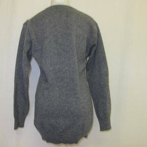 May include: A gray long-sleeved sweater with a v-neck.
