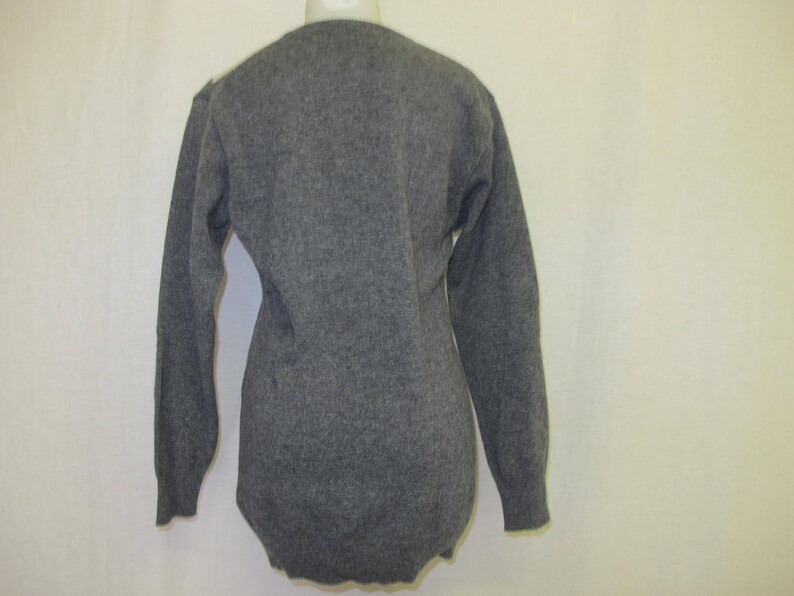 May include: A gray long-sleeved sweater with a v-neck.