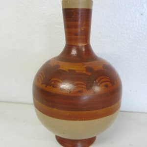 Op de afbeelding: Een kleine, handbeschilderde keramische vaas met een bruin en beige kleurenschema. De vaas heeft een rond lichaam en een smalle hals. Het heeft een decoratief patroon van bruine lijnen en swirls.