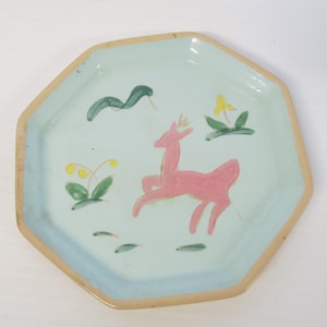 May include: A light blue octagonal ceramic plate with a hand-painted design of a pink deer, green leaves, and yellow flowers.