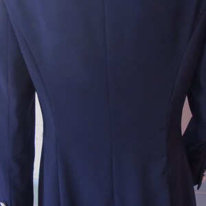 May include: A navy blue blazer with a white collar and trim. The blazer has a single button closure and long sleeves.