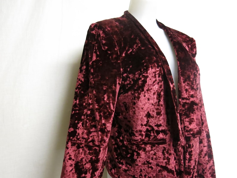 May include: A burgundy crushed velvet blazer with a deep V-neck and long sleeves.