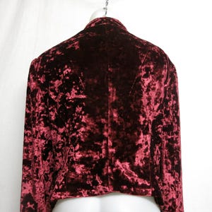 May include: A red crushed velvet jacket with long sleeves. The jacket has a cropped length and a classic collar.